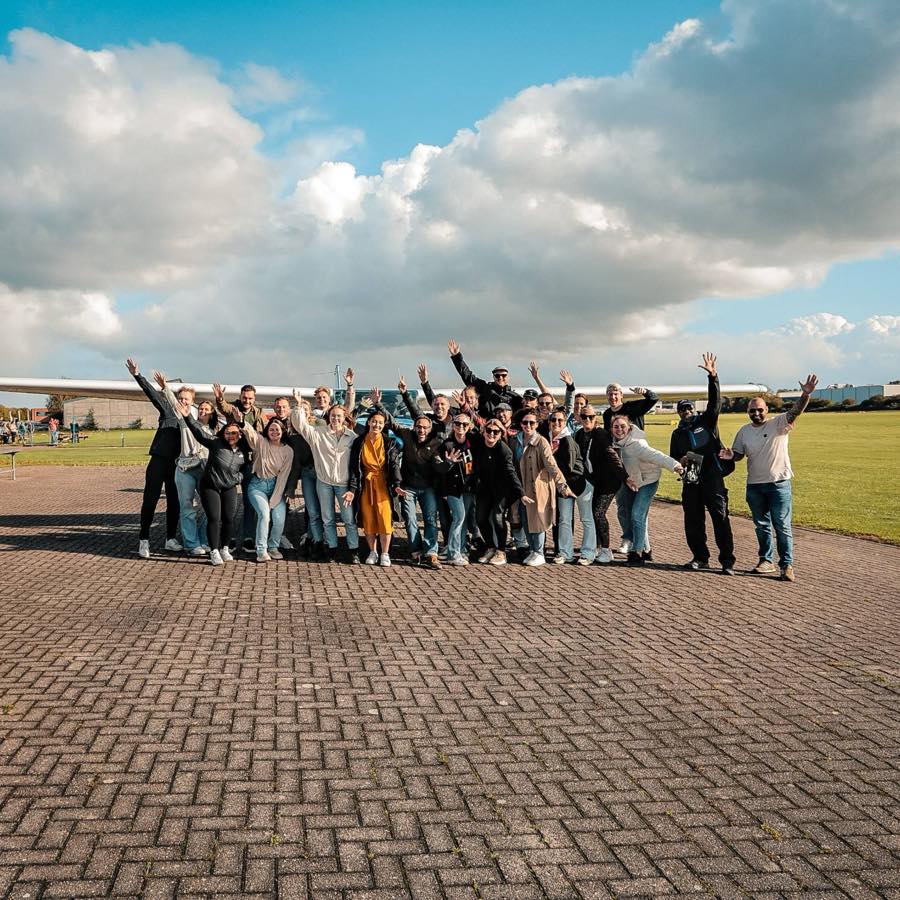 Het team van Diezit op een vliegveld, zwaaiend voor een sportvliegtuig